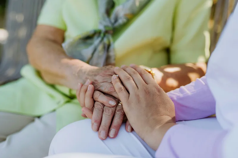 Caring hands holding an elderly person's hand