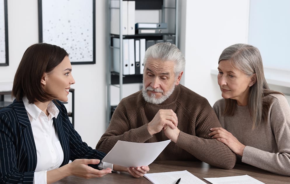 Adult children and aging parents reviewing long-term care planning documents around a kitchen table