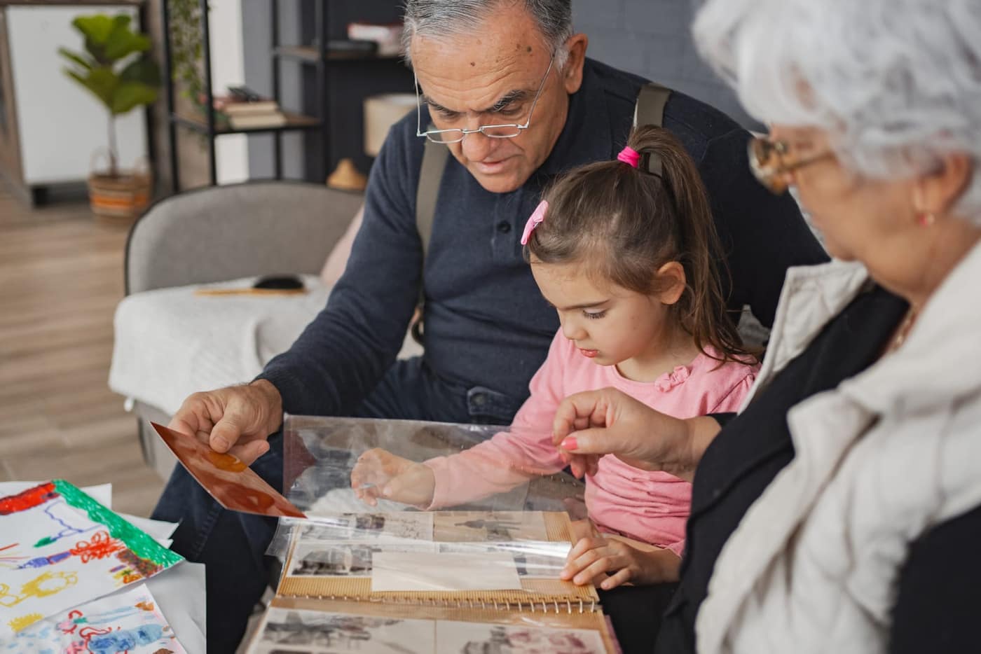 Grandparents sharing stories with granddaughter while looking through a photo album together