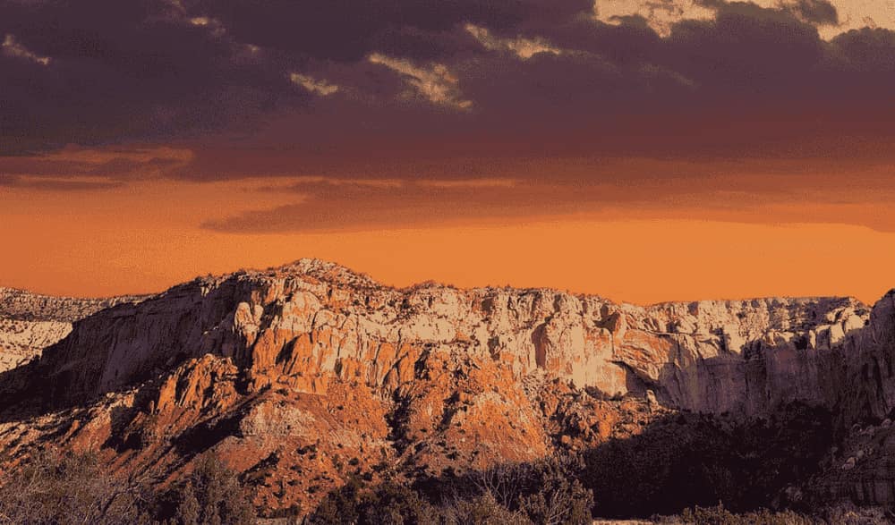 Sunlit desert mesa cliffs under an orange sky in New Mexico